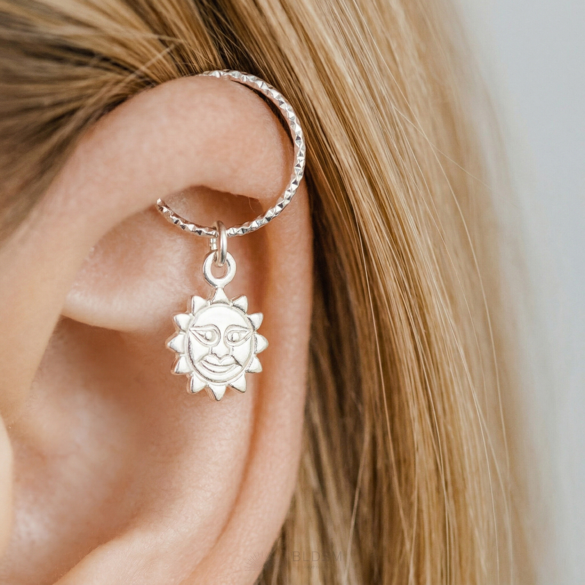 925 Sterling Silver endless hoop earring with a smiling sun charm pendant on a person's helix piercing.