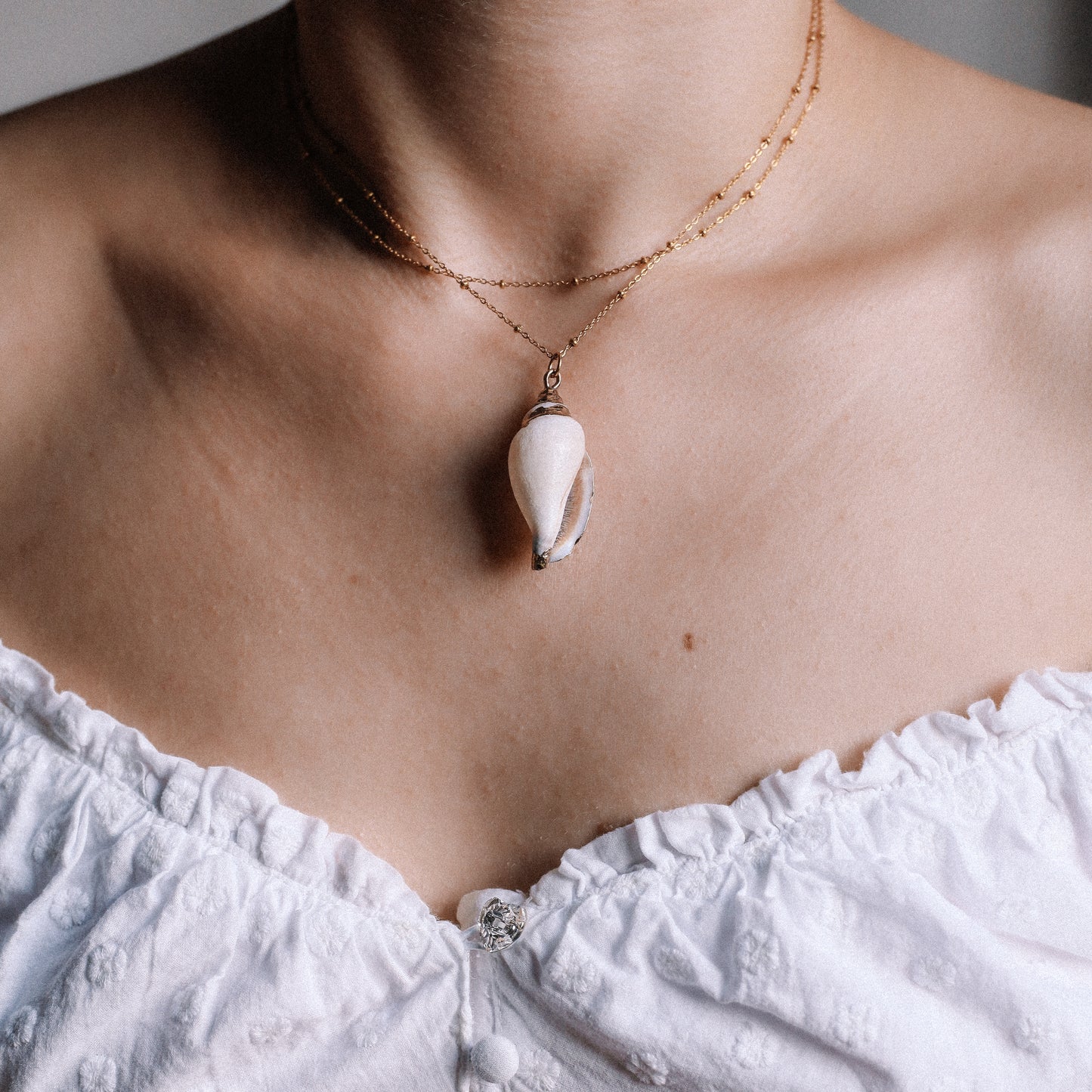 Delicate gold necklace with a real conch shell, perfect for adding ocean-inspired style to any outfit.