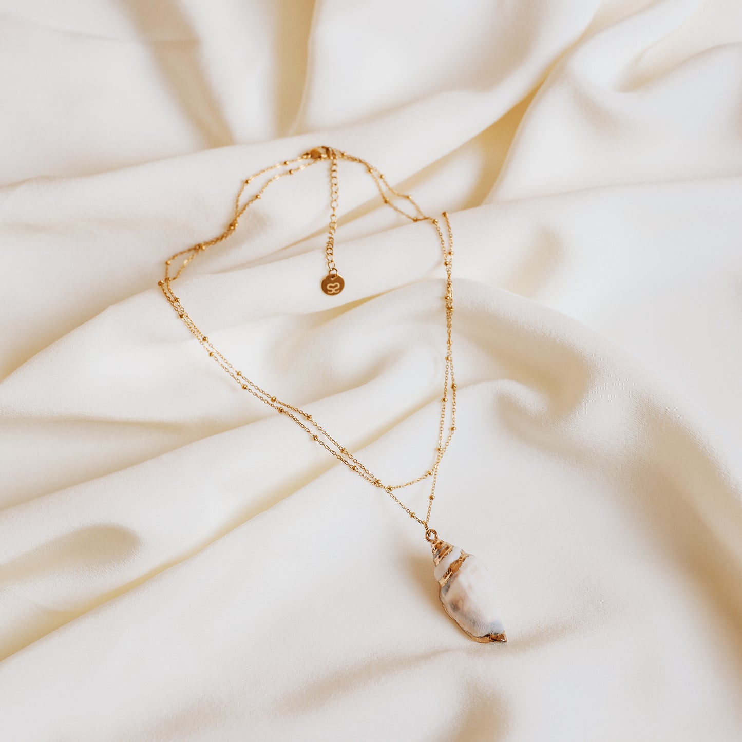Delicate gold necklace with a real conch shell, perfect for adding ocean-inspired style to any outfit.