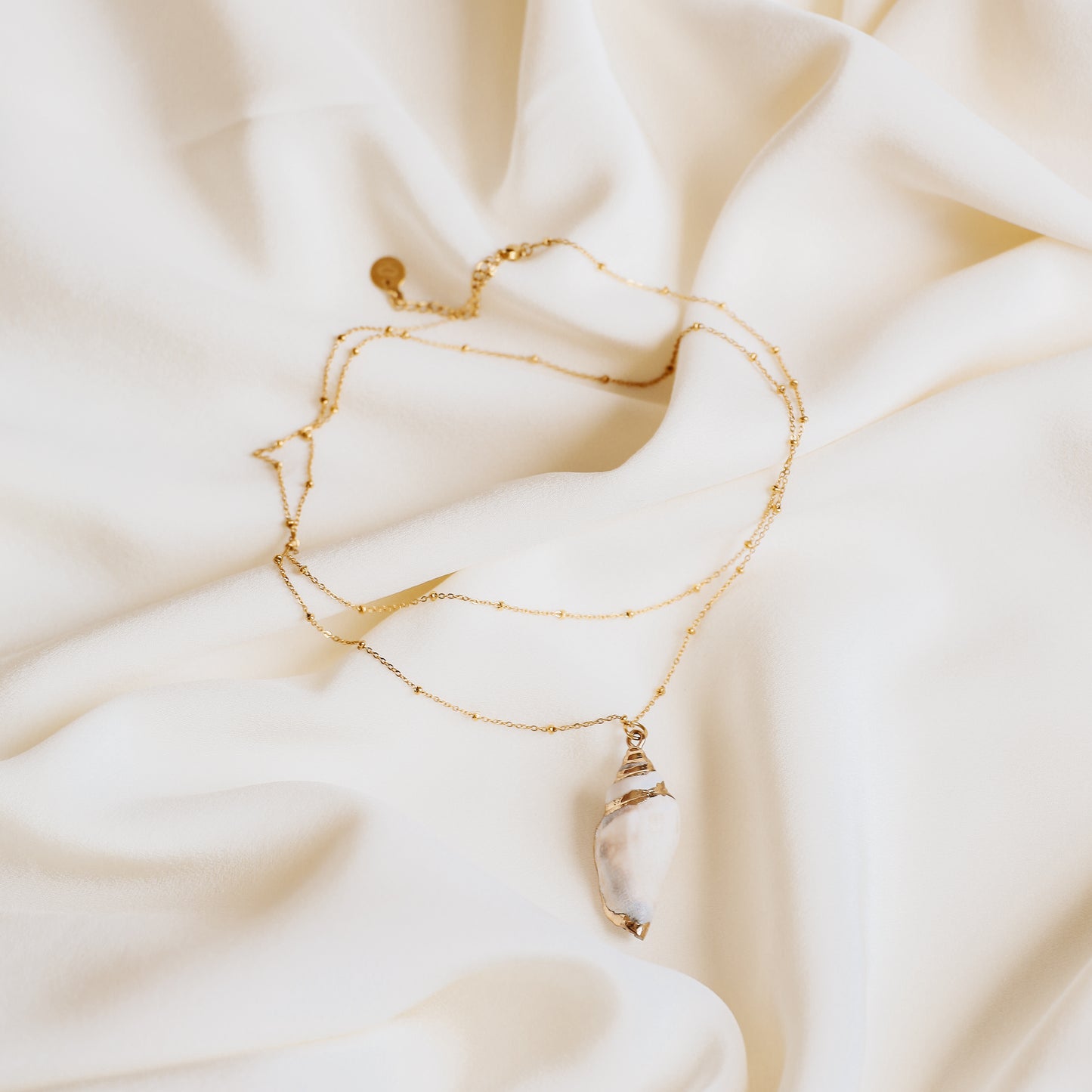 Delicate gold necklace with a real conch shell, perfect for adding ocean-inspired style to any outfit.
