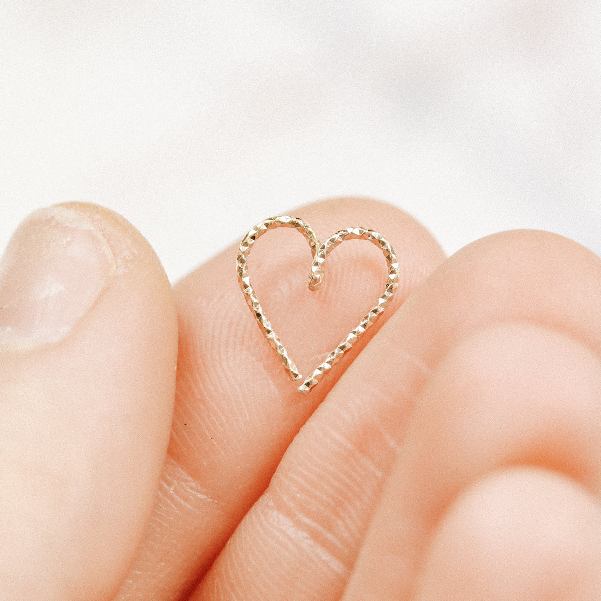 Close-up of an 18k gold plated diamond-cut heart hoop showing the textured finish.