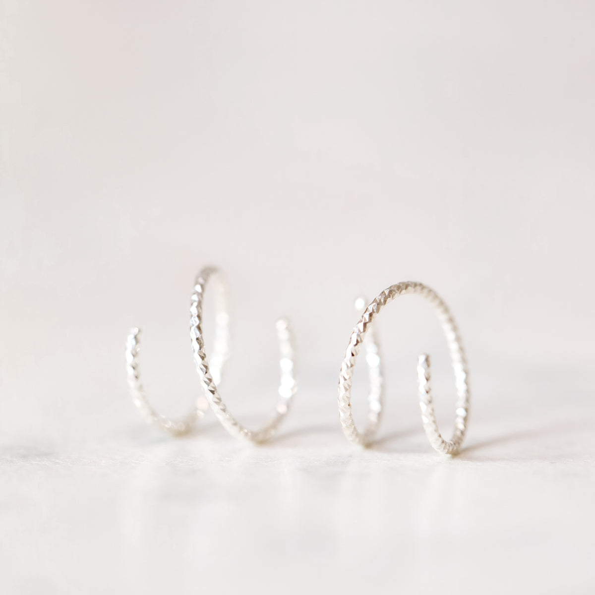 Minimal silver double hoop earrings on ear, tiny spiral earrings, sterling silver illusion double piercing jewelry