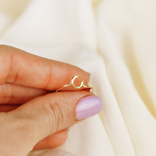 Delicate handmade gold wire ring with a lowercase cursive letter C, worn on a hand.