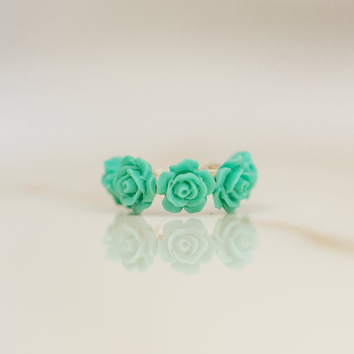 Turquoise aqua blue resin rose conch ear cuff worn on the ear as a colorful floral cartilage cuff