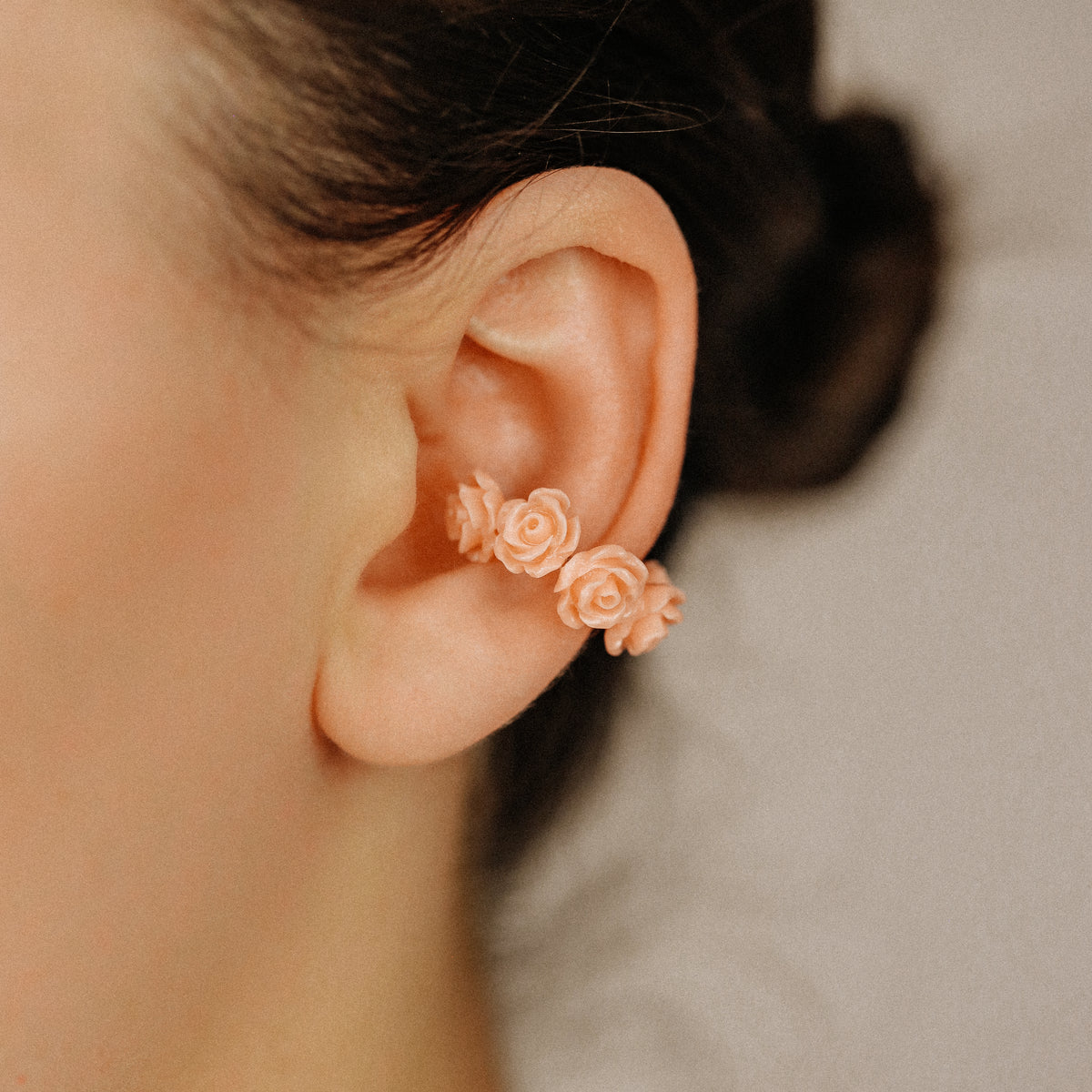 Peach coral resin rose ear cuff worn on the conch area with romantic floral detail