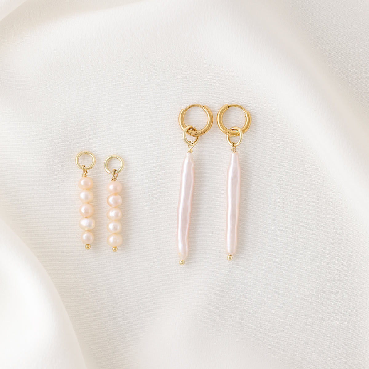 An overhead view showing the individual components of the earrings: two gold hoops, two pink pearl cluster charms, and two long linear stick pearls.