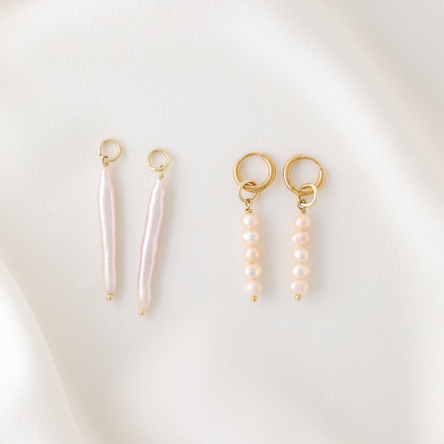An overhead view showing the individual components of the earrings: two gold hoops, two pink pearl cluster charms, and two long linear stick pearls.