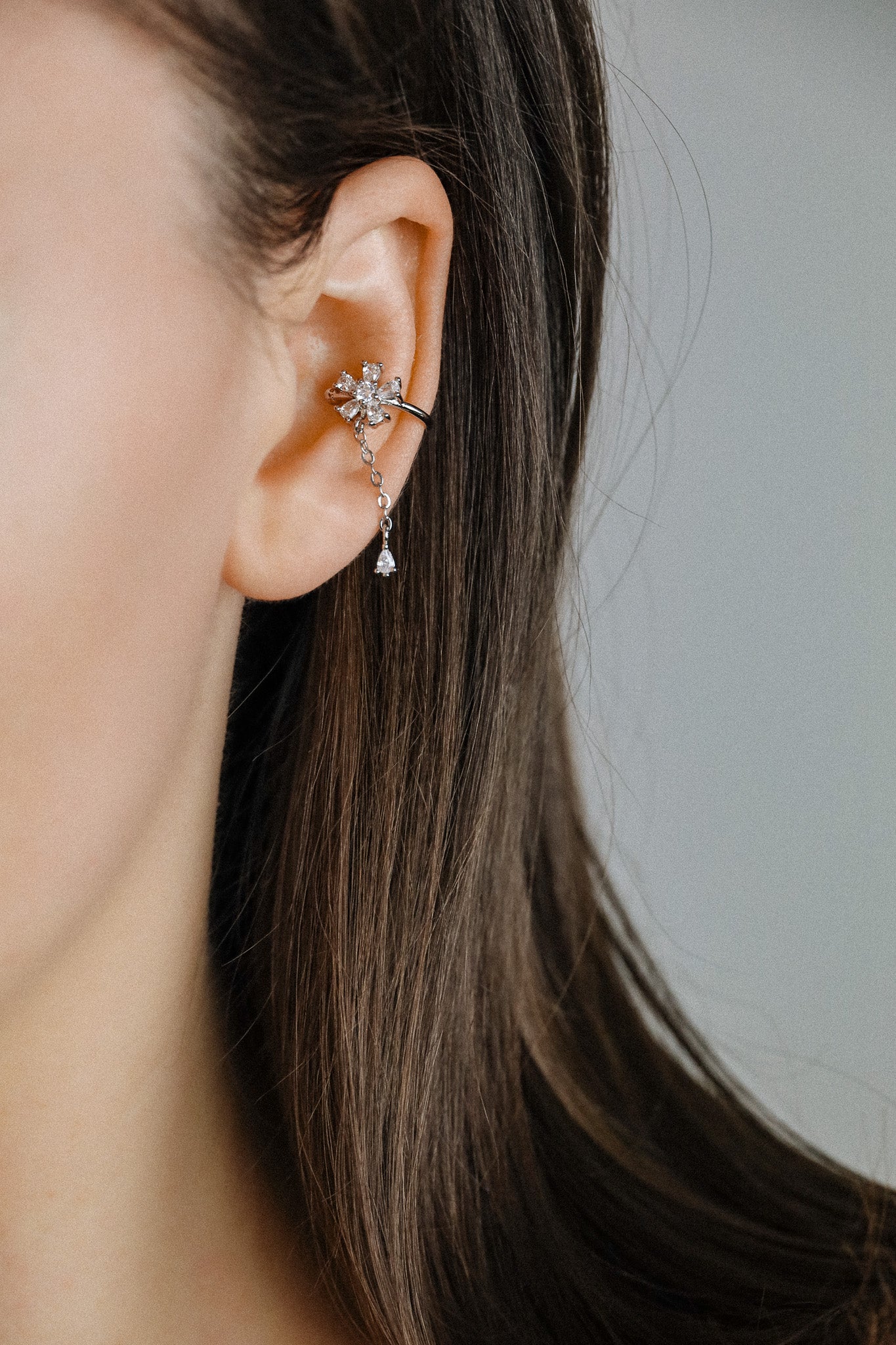 Sparkling flower ear cuff with dainty drop chain in 18k gold plated sterling silver and 925 silver, worn on cartilage without piercing.