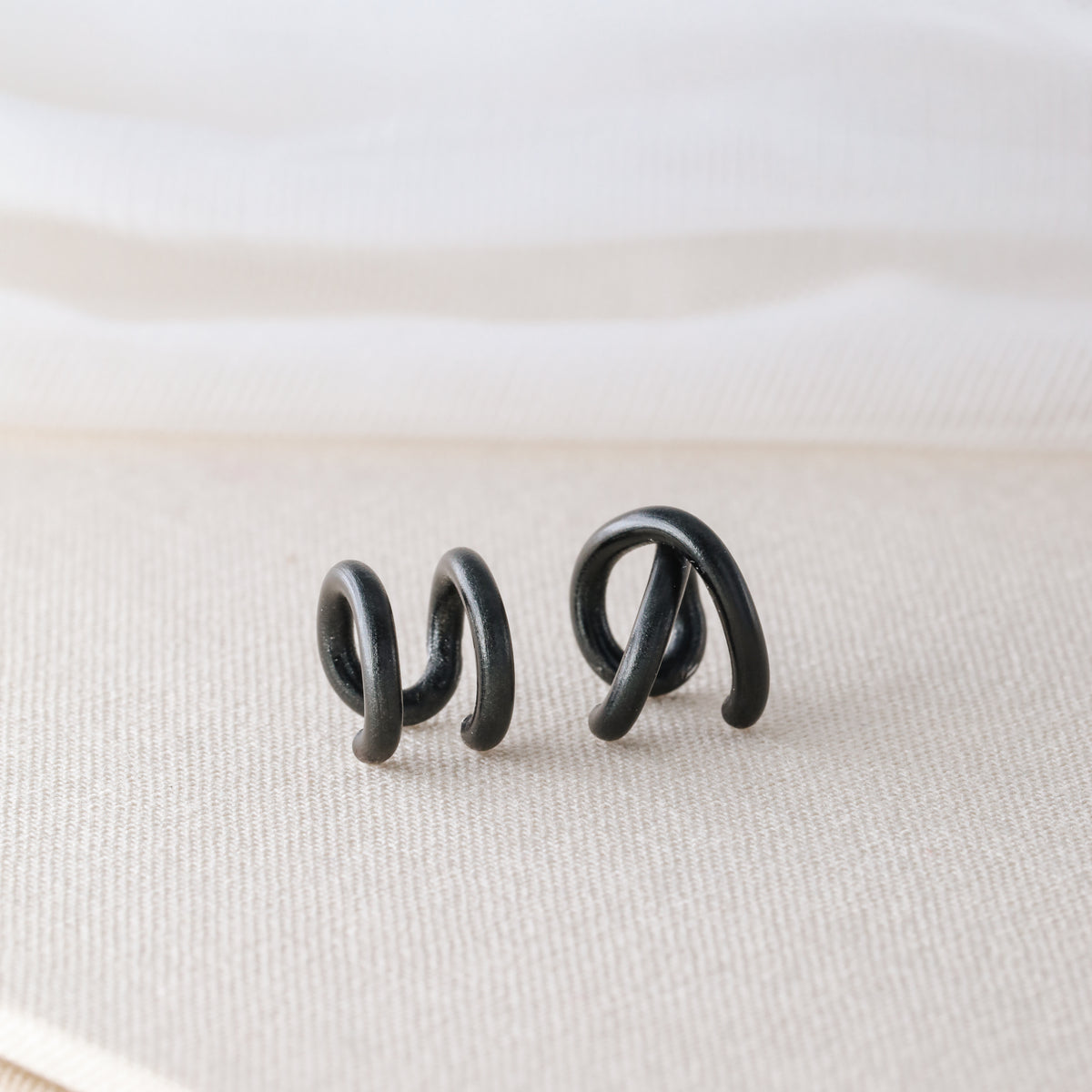 Adjustable no-piercing helix ear cuff shown worn on the upper cartilage area, available in silver, black and soft gold with Double Line and Criss-Cross style options for a bold stacked ear look.