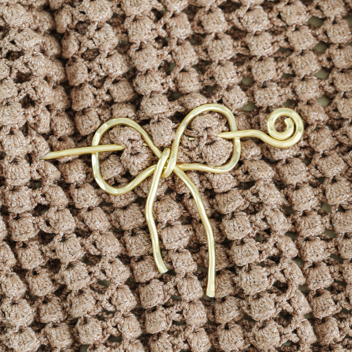 Handmade aluminum bow shawl pin brooch with matching removable stick pin, shown in gold and available in silver or gold finish, designed as a decorative and functional scarf fastener for shawls, sweaters, cardigans, knit wraps and crochet pieces, with a romantic bow shape and minimalist metal design.