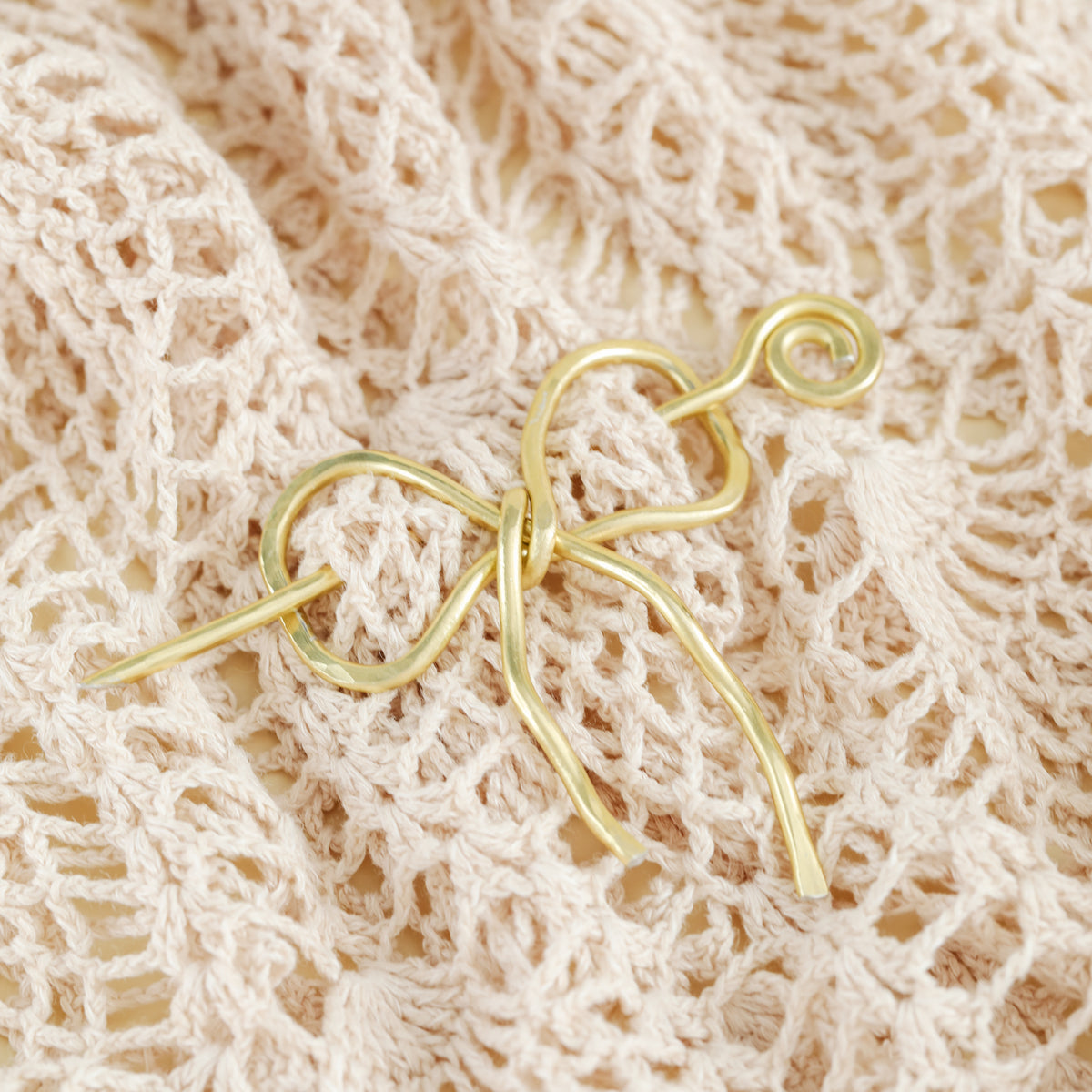 Handmade aluminum bow shawl pin brooch with matching removable stick pin, shown in gold and available in silver or gold finish, designed as a decorative and functional scarf fastener for shawls, sweaters, cardigans, knit wraps and crochet pieces, with a romantic bow shape and minimalist metal design.