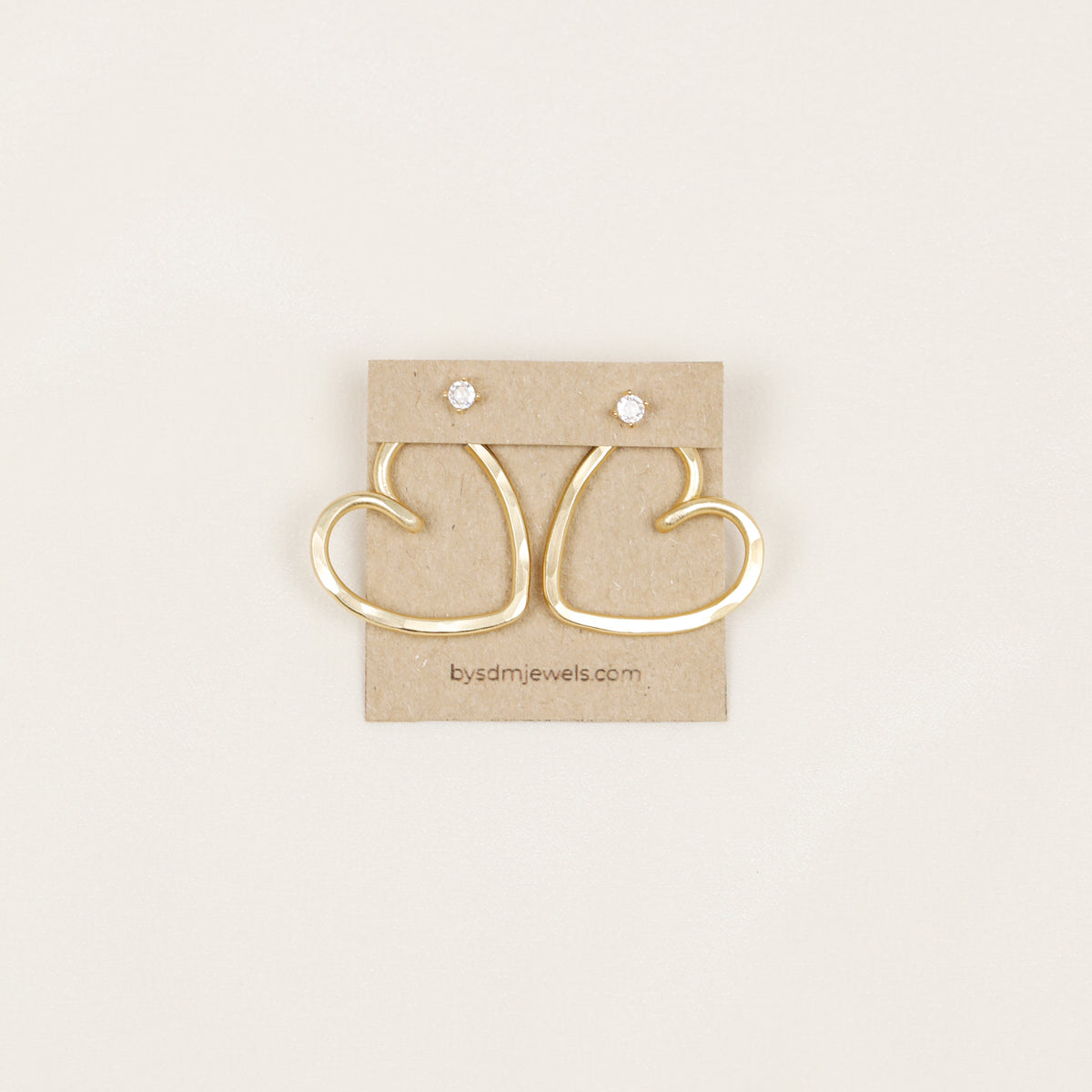 Handmade open heart Ear Jacket earrings designed to sit behind the pierced earlobe beneath an interchangeable stud, available as One Ear Jacket or a matching Pair of Ear Jackets in gold or silver hammered aluminum, approximately 25 mm in diameter, with stainless steel post studs; one surprise pair of stud earrings is included with each order and selected from currently available styles, so the studs shown in the photos are examples and specific designs cannot be guaranteed.