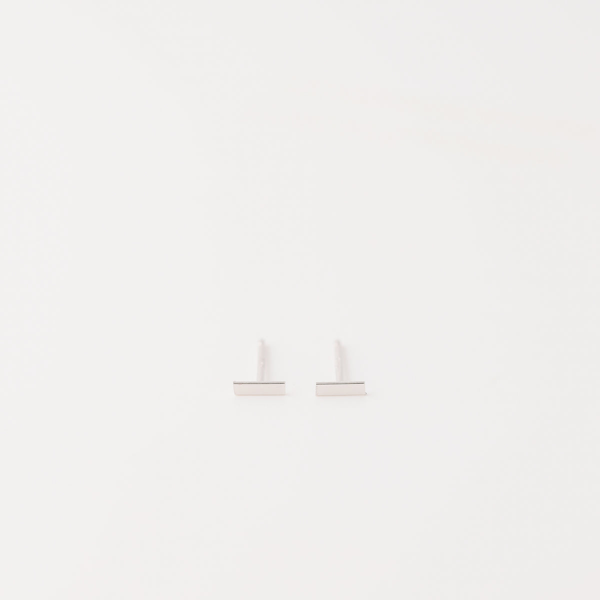 Tiny rectangle bar stud earrings in solid 925 sterling silver on white background