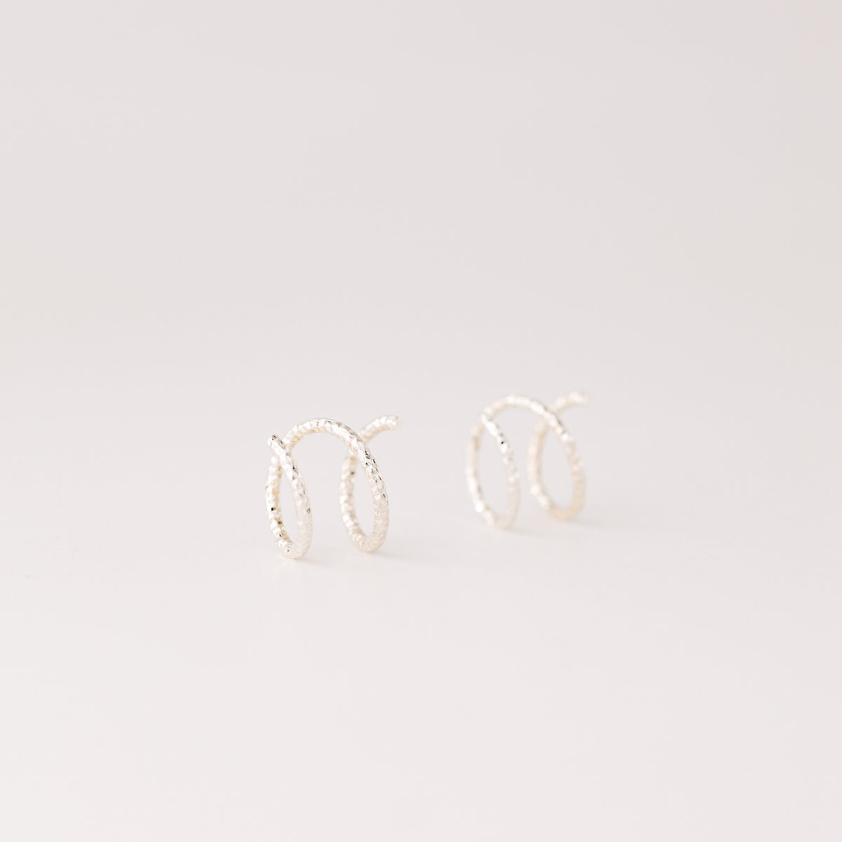 Minimal silver double hoop earrings on ear, tiny spiral earrings, sterling silver illusion double piercing jewelry