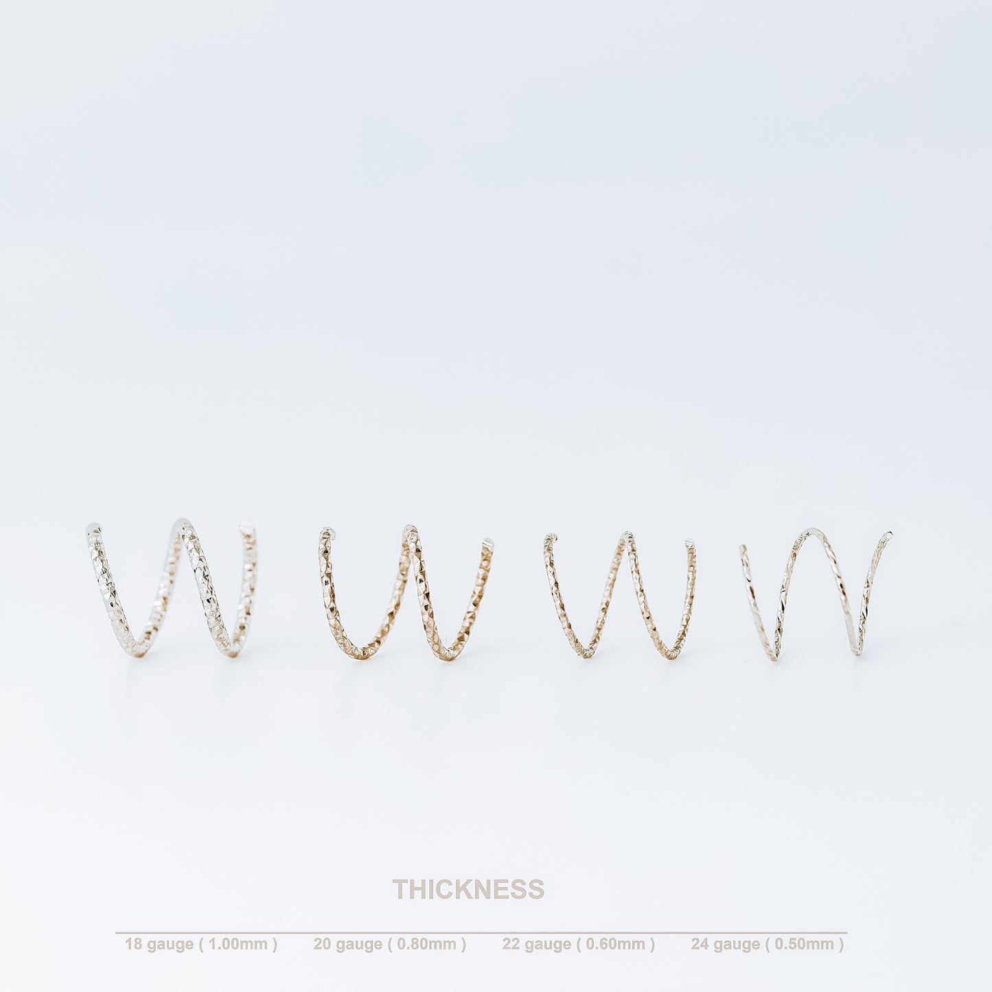 Minimal black double hoop spiral earrings worn on ear, tiny ruthenium sterling silver illusion hoops creating double piercing look, diamond cut texture close-up