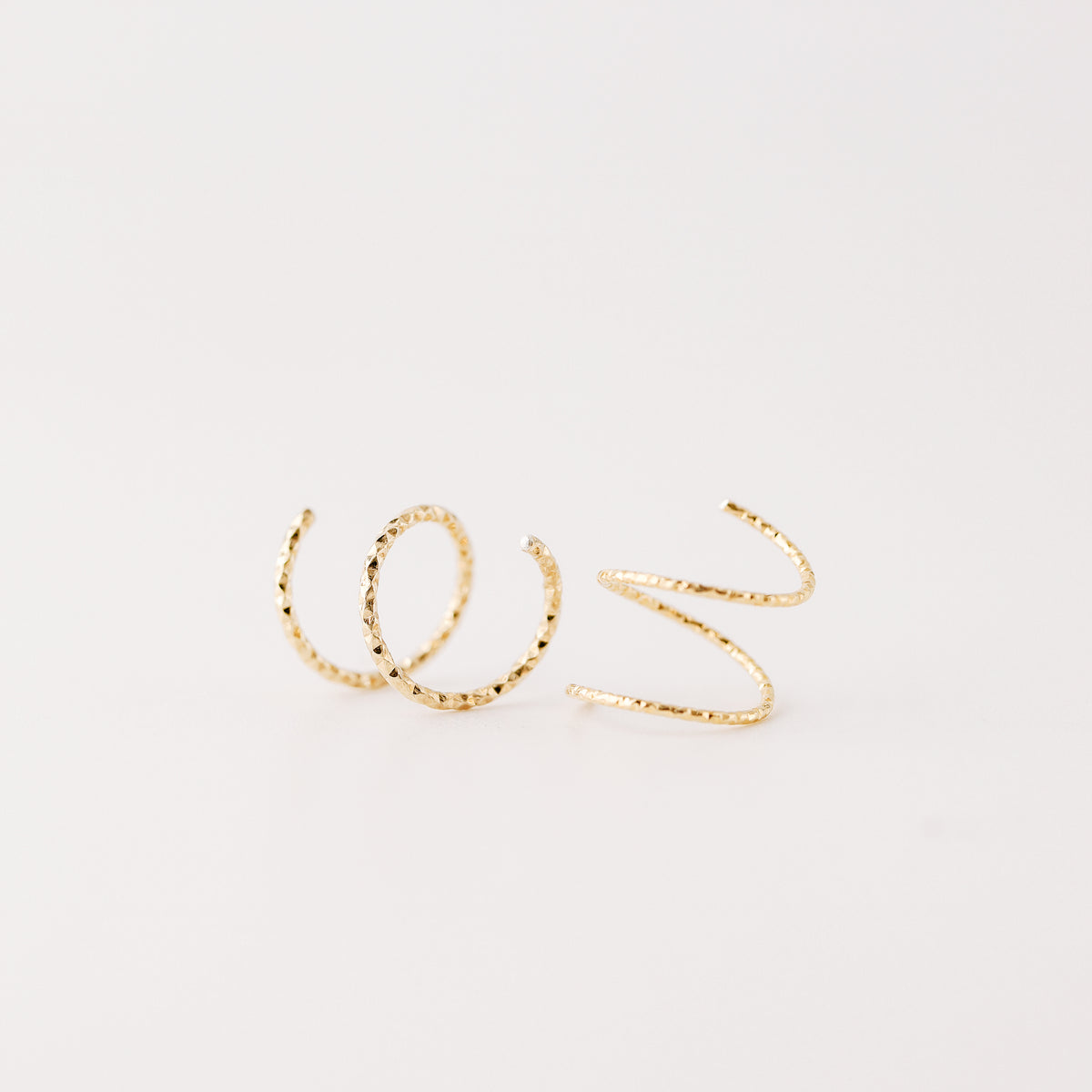 Minimal gold double hoop earrings with spiral twist design worn on ear, illusion of double piercing, diamond cut sterling silver jewelry