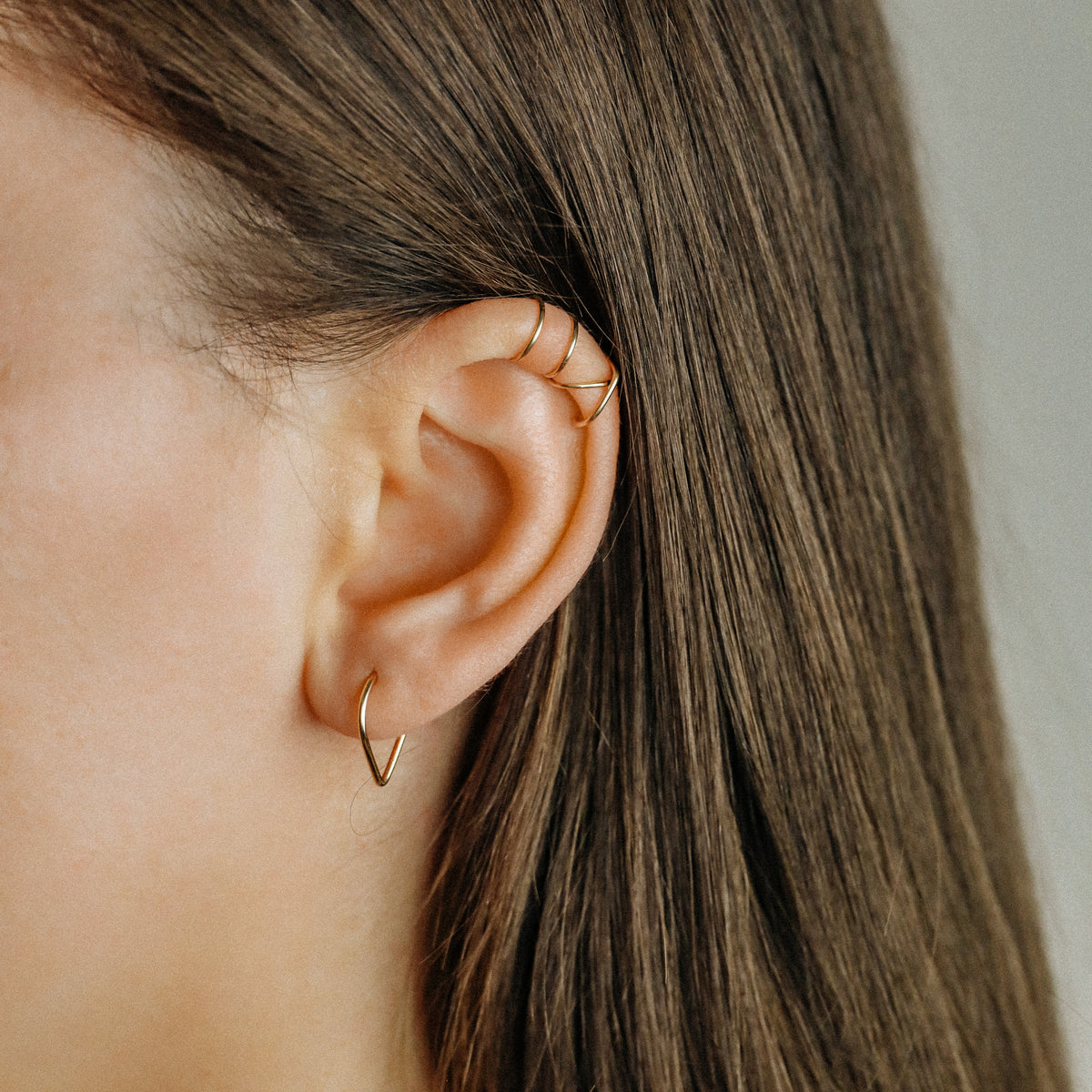 Model wearing a gold chevron septum ring with a minimal V-shaped front.
