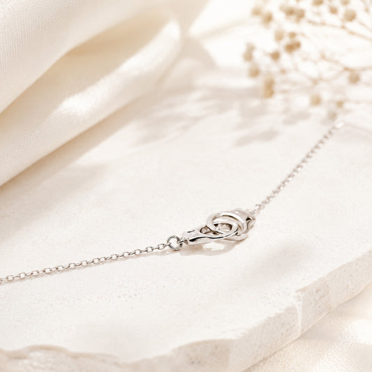 Sterling silver handcuff necklace displayed on light marble surface with soft natural light