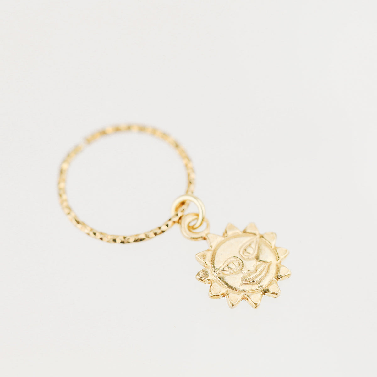 High-resolution shot of a single 18k gold plated sun charm hoop earring on a white background.