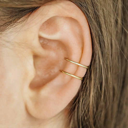Gold double band ear cuff worn on the upper ear, featuring a slim no piercing design with diamond cut sparkle texture.