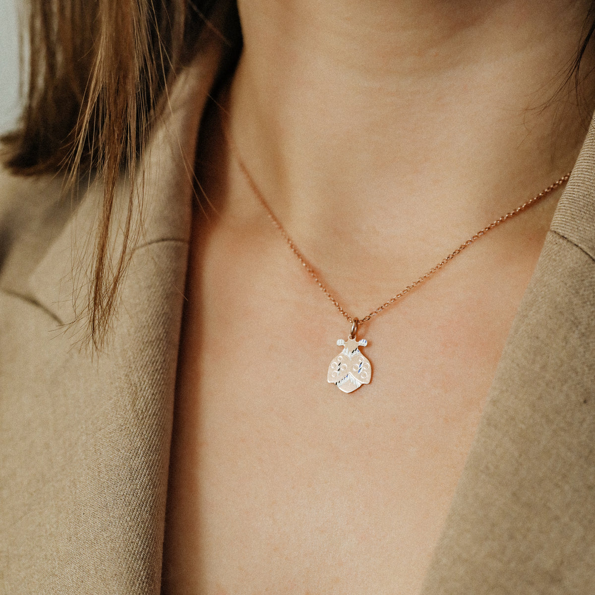 Ladybug necklace worn by model with beige blazer for elegant everyday styling
