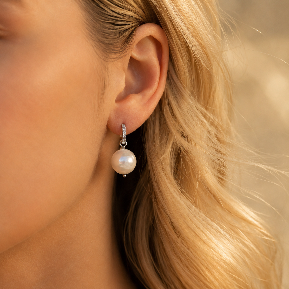 Pearl drop hoop earring worn on blonde model in warm golden light with elegant dangle design