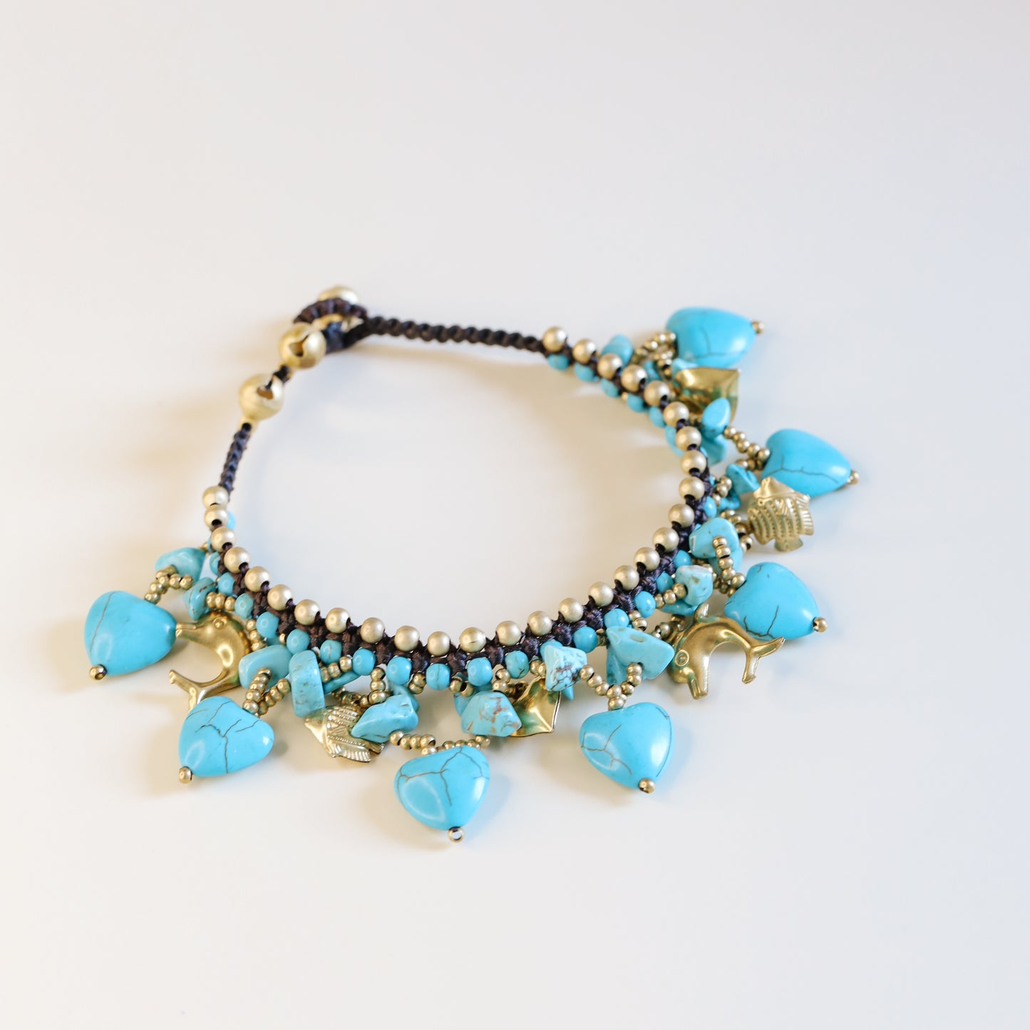 Close-up of the brown waxed cord and adjustable loop closure with small gold-tone bells on the turquoise anklet.