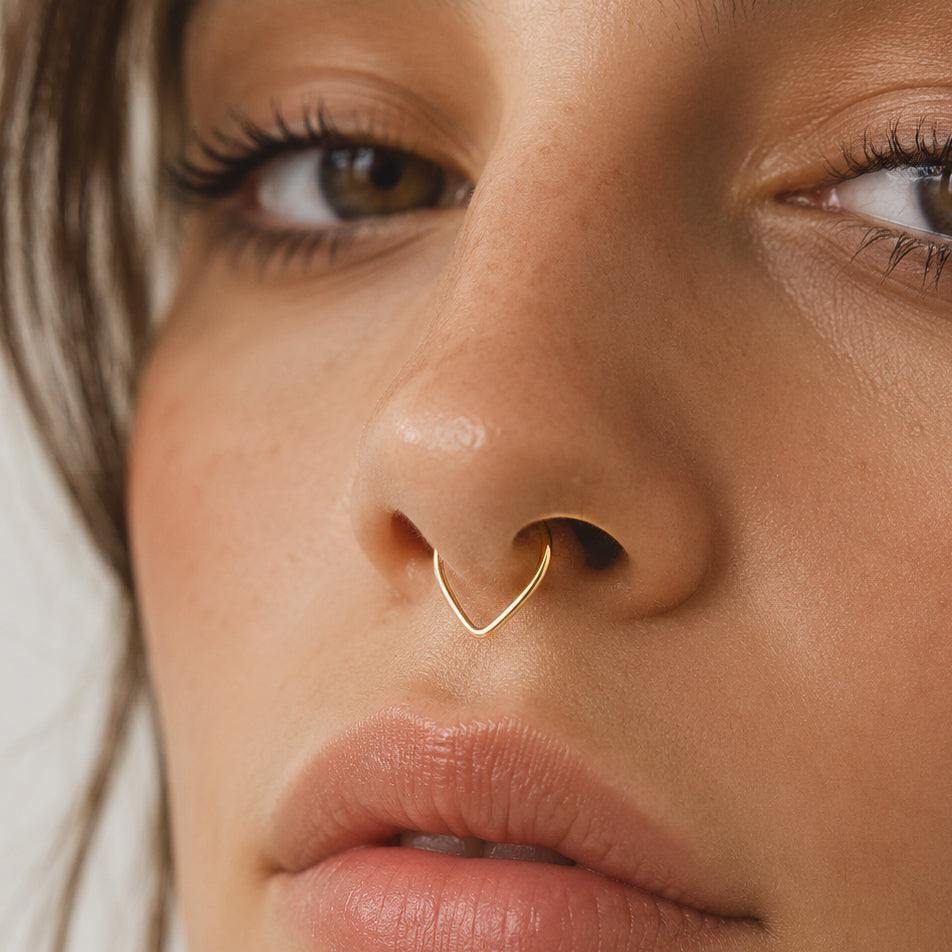 Model wearing a gold chevron septum ring with a minimal V-shaped front.