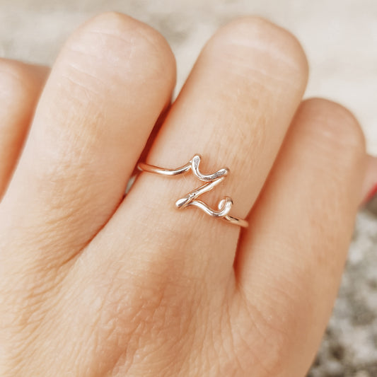 Handmade gold wire ring featuring a lowercase cursive letter Z, styled on a hand with elegant red french nails.