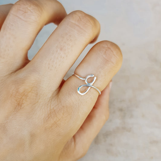 Close-up of a handmade 925 sterling silver wire ring shaped into the letter G on a woman's finger.