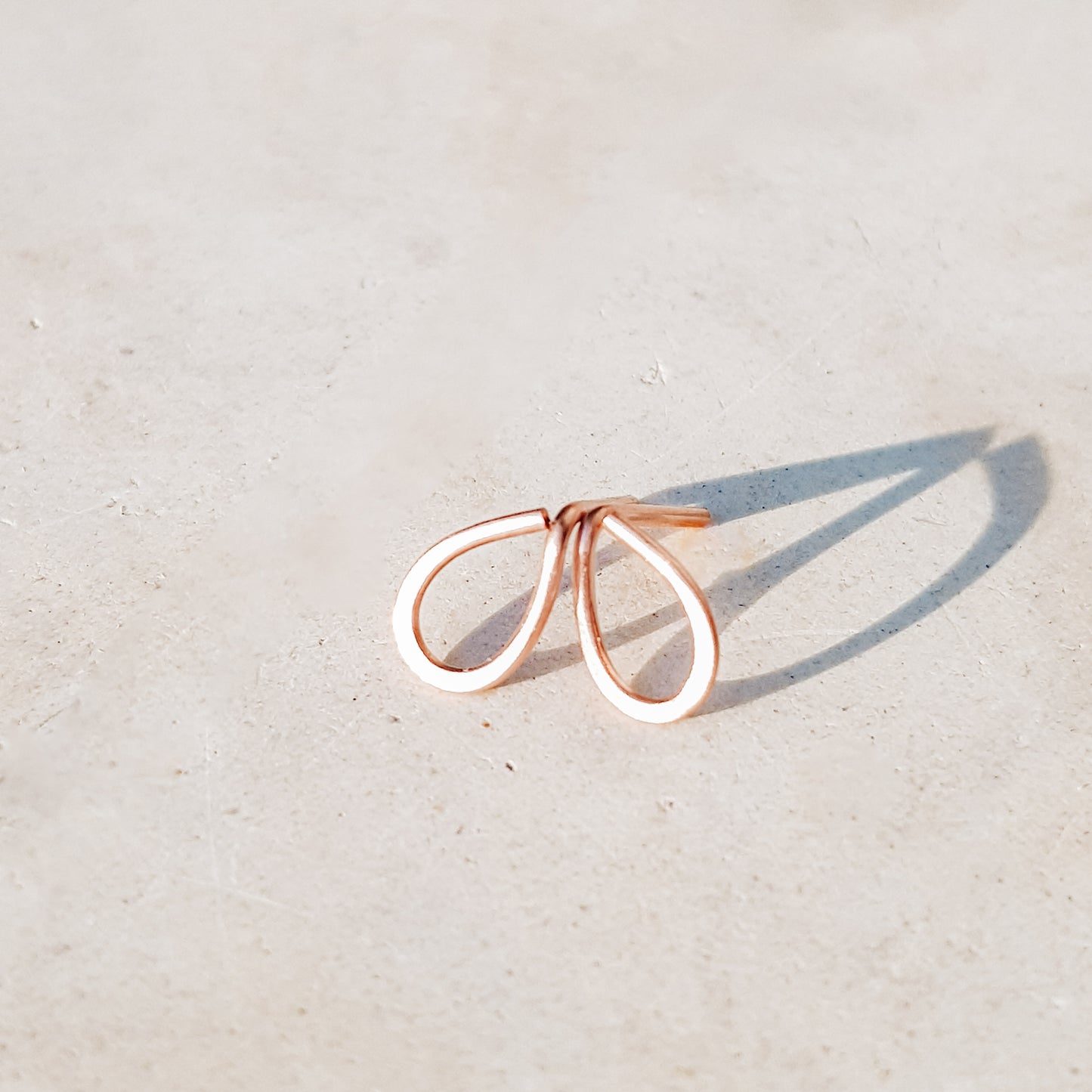 Minimal open drop stud earrings in gold filled sterling silver on neutral background with soft natural light