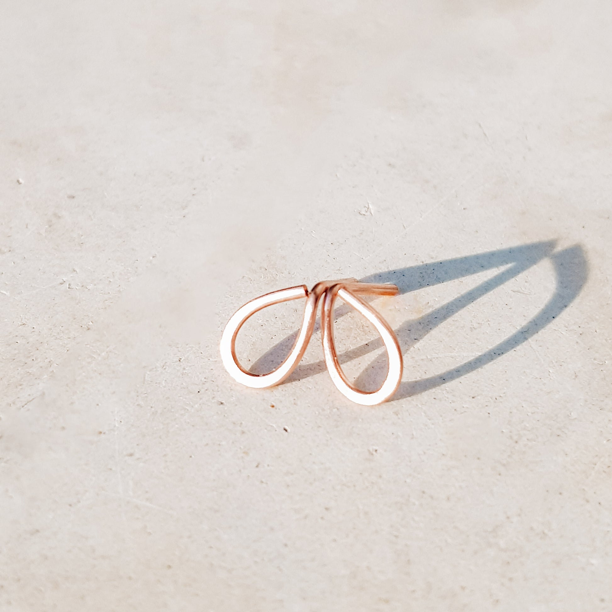 Minimal open drop stud earrings in gold filled sterling silver on neutral background with soft natural light