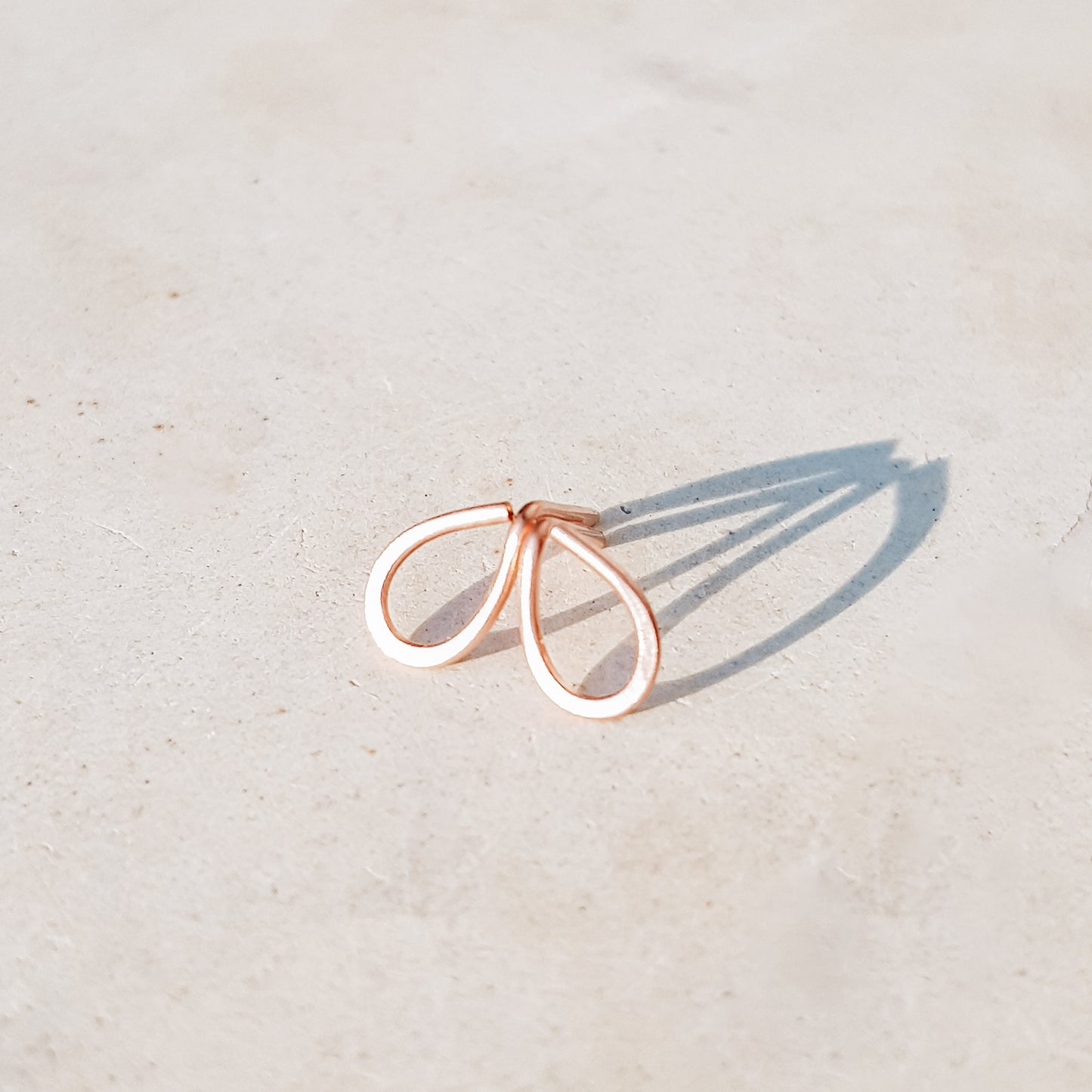 Minimal open drop stud earrings in gold filled sterling silver on neutral background with soft natural light