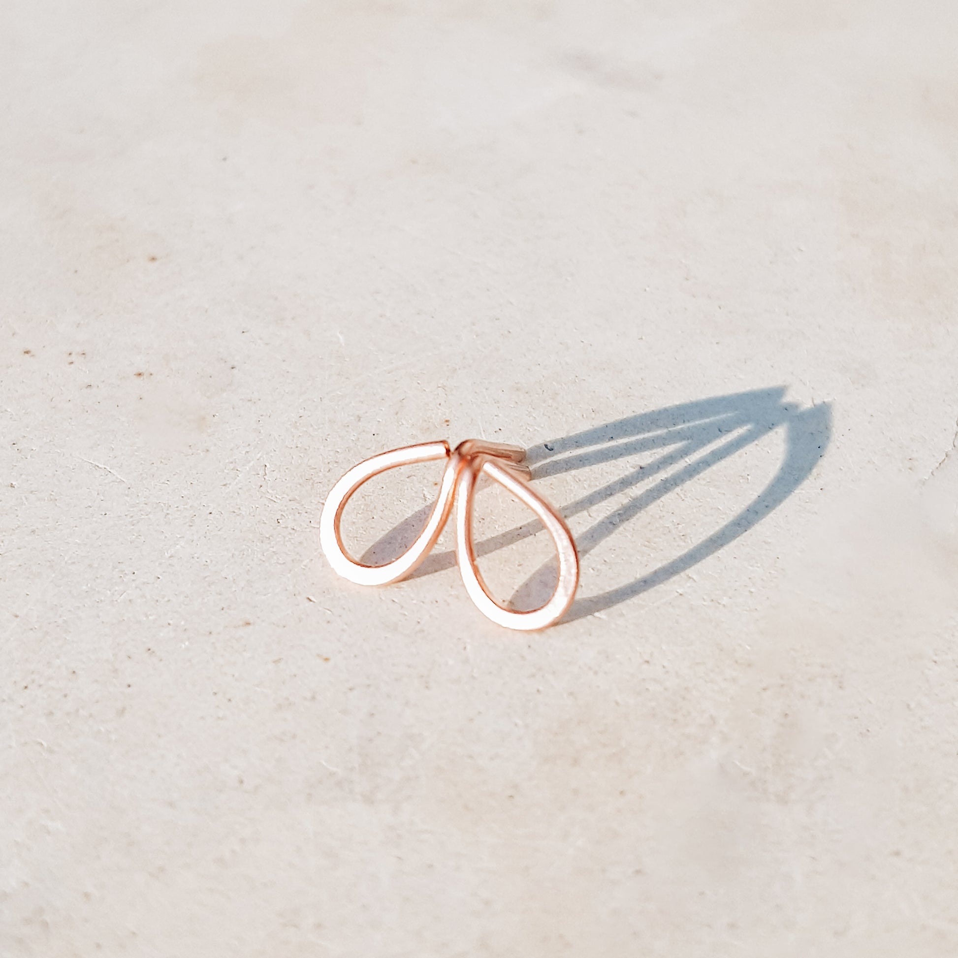 Minimal open drop stud earrings in gold filled sterling silver on neutral background with soft natural light