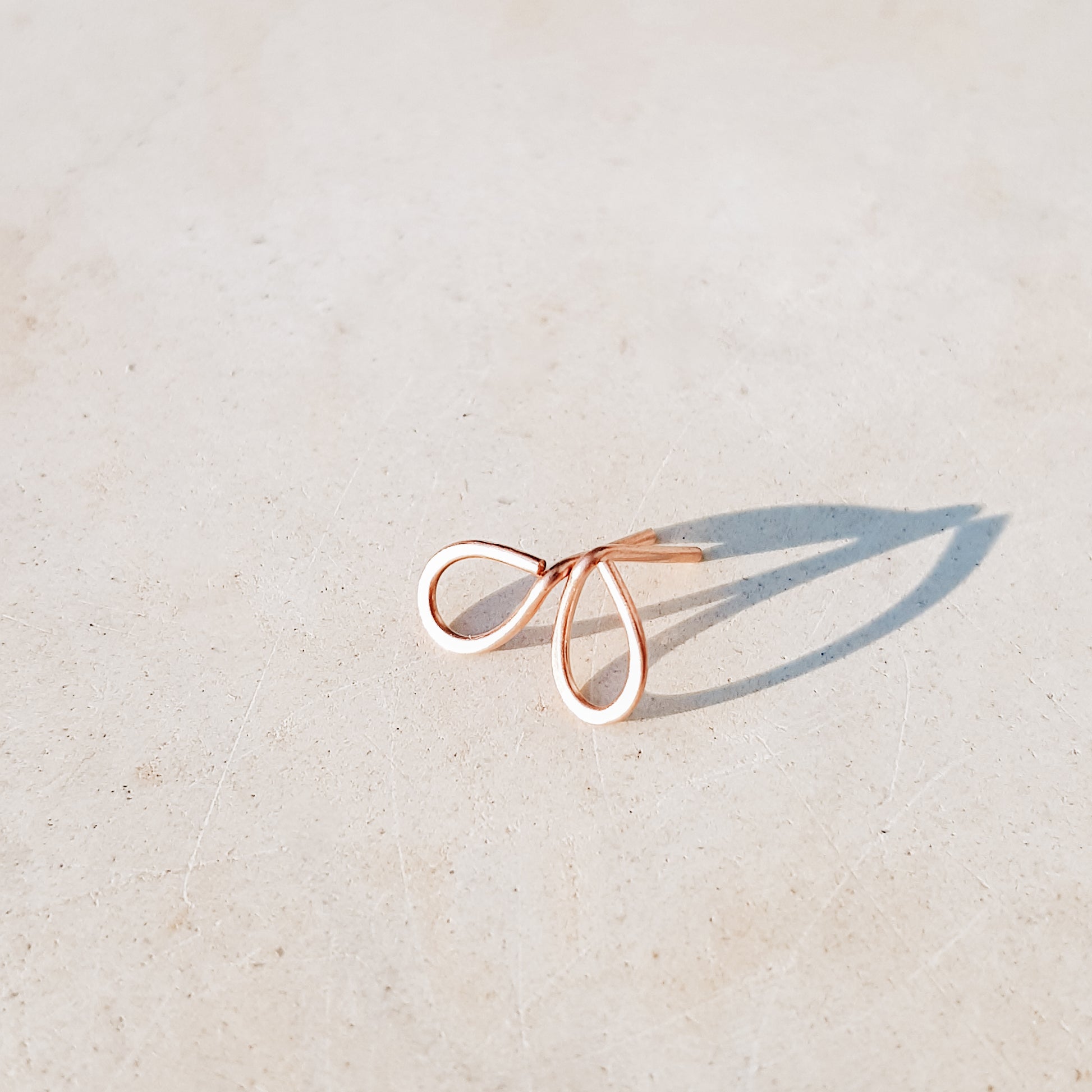 Minimal open drop stud earrings in gold filled sterling silver on neutral background with soft natural light