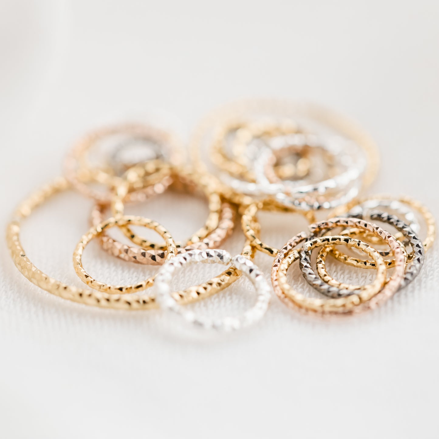 Detailed view of 18k rose gold faceted endless hoops showing the diamond-cut texture.