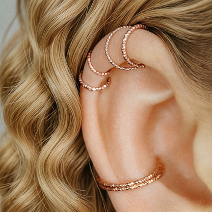 Multiple textured rose gold hoops styled in helix and lobe piercings for an ear party look.
