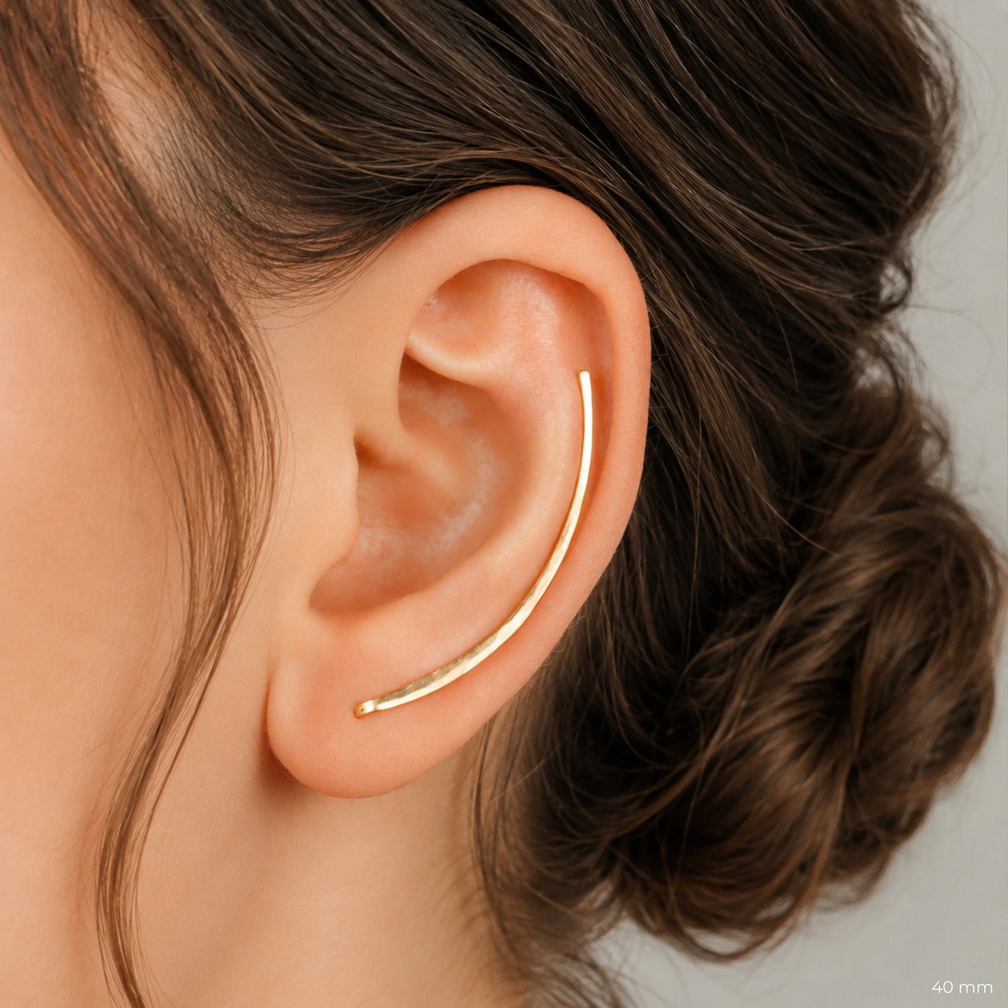 40 mm handmade hammered ear climber shown on the ear, shaped as a long minimalist bar earring that follows the natural outer curve of the ear. Elegant ear crawler design with slim reflective wire, available in solid 925 sterling silver, 14k gold filled and 14k rose gold filled, sold as single left, single right or pair.