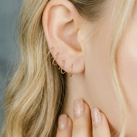 Minimal gold double hoop earrings with spiral twist design worn on ear, illusion of double piercing, diamond cut sterling silver jewelry