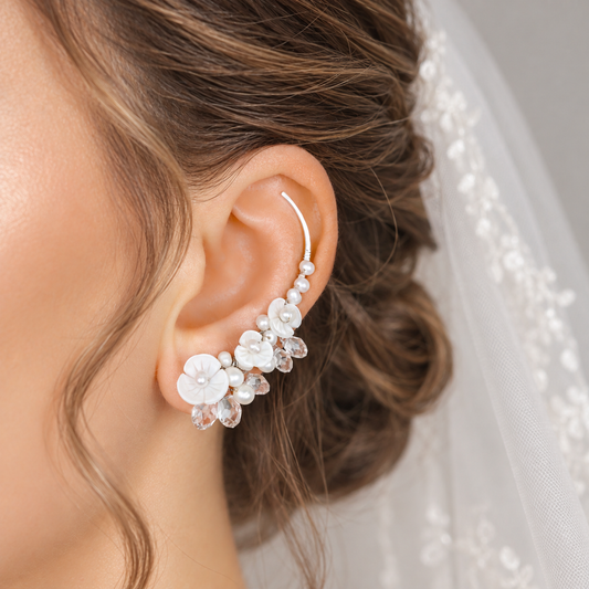 Bridal ear crawler worn with a formal updo and veil, decorated with genuine freshwater pearls, luminous flower shapes and clear crystal briolettes for a detailed wedding look.