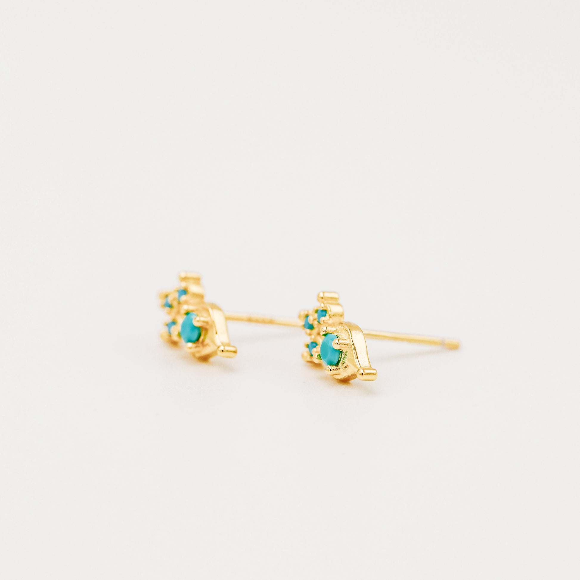 Gold turquoise earrings shown from side profile on white background