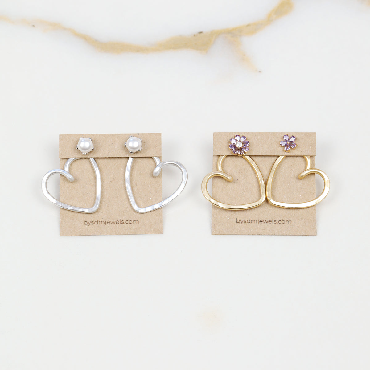 Handmade open heart Ear Jacket earrings designed to sit behind the pierced earlobe beneath an interchangeable stud, available as one Ear Jacket or a matching pair in gold or silver hammered aluminum, approximately 25 mm in diameter, with one coordinating pair of stainless steel post stud earrings included with each order; stud designs vary according to current availability and those shown in the photos are styling examples rather than guaranteed designs.