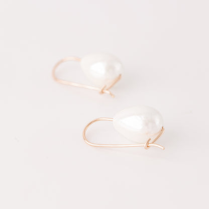 Handmade ceramic pearl teardrop earrings featuring large white pear-shaped pearls approximately 20 mm x 15 mm suspended from a minimalist curved wire hook, approximately 30 mm total length, available in solid 925 sterling silver, 14k gold filled or 14k rose gold filled.