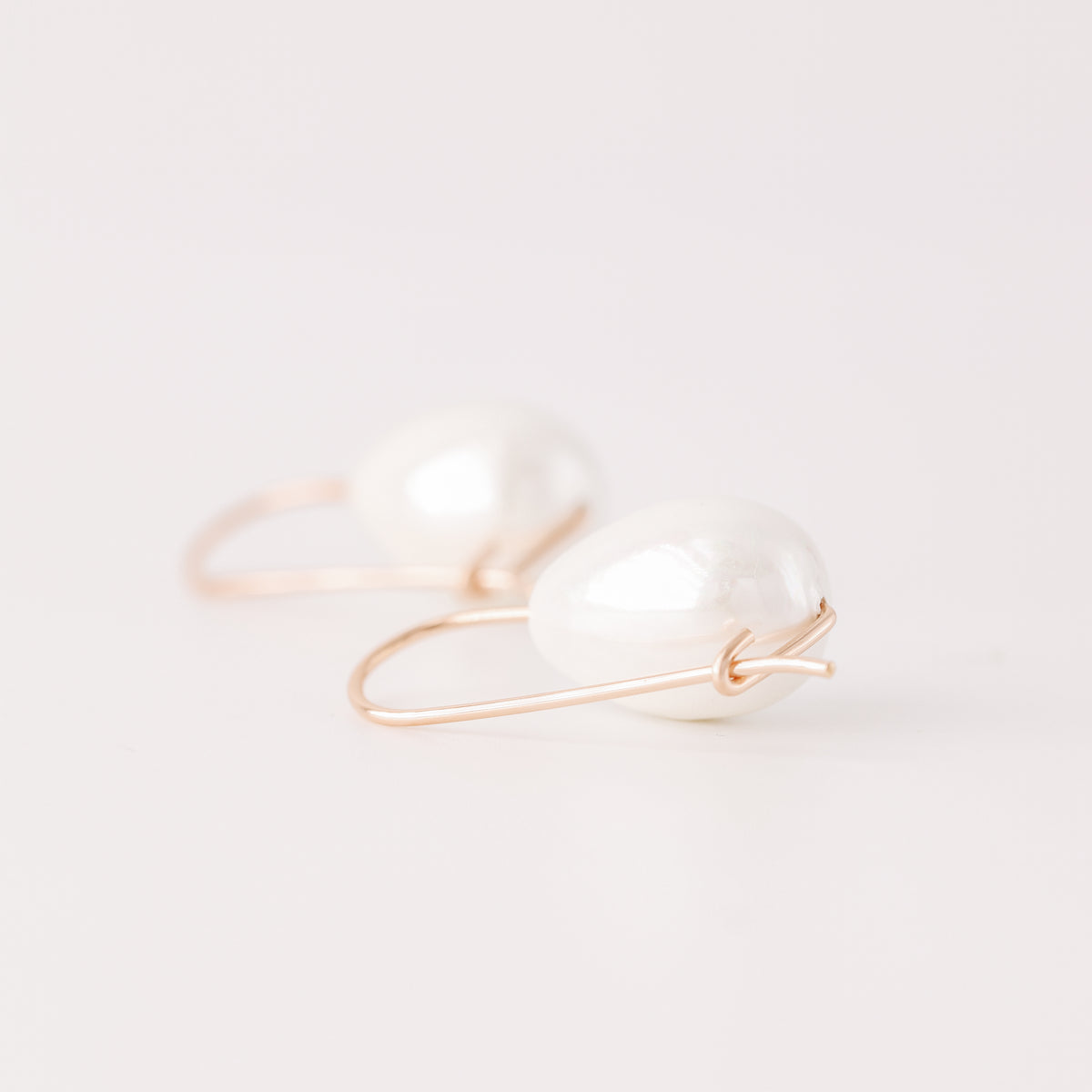 Handmade ceramic pearl teardrop earrings featuring large white pear-shaped pearls approximately 20 mm x 15 mm suspended from a minimalist curved wire hook, approximately 30 mm total length, available in solid 925 sterling silver, 14k gold filled or 14k rose gold filled.