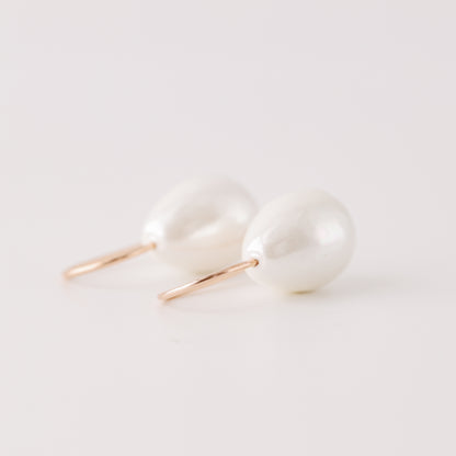 Handmade ceramic pearl teardrop earrings featuring large white pear-shaped pearls approximately 20 mm x 15 mm suspended from a minimalist curved wire hook, approximately 30 mm total length, available in solid 925 sterling silver, 14k gold filled or 14k rose gold filled.