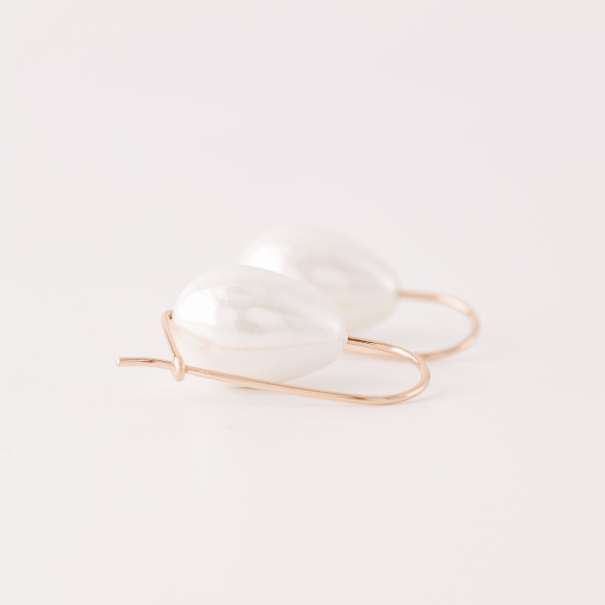 Handmade ceramic pearl teardrop earrings featuring large white pear-shaped pearls approximately 20 mm x 15 mm suspended from a minimalist curved wire hook, approximately 30 mm total length, available in solid 925 sterling silver, 14k gold filled or 14k rose gold filled.