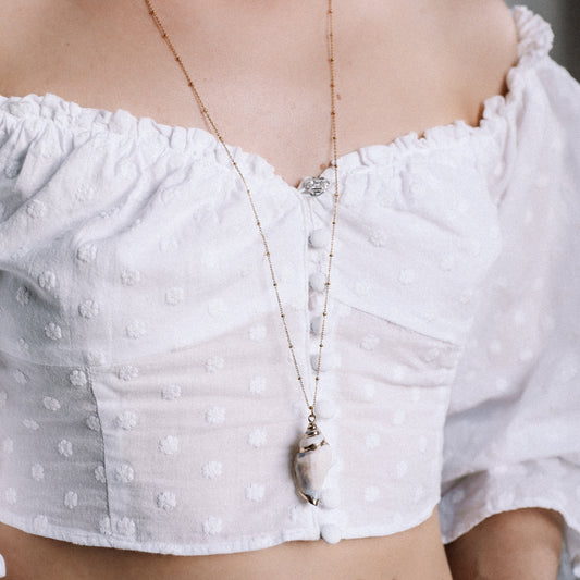 Delicate gold necklace with a real conch shell, perfect for adding ocean-inspired style to any outfit.