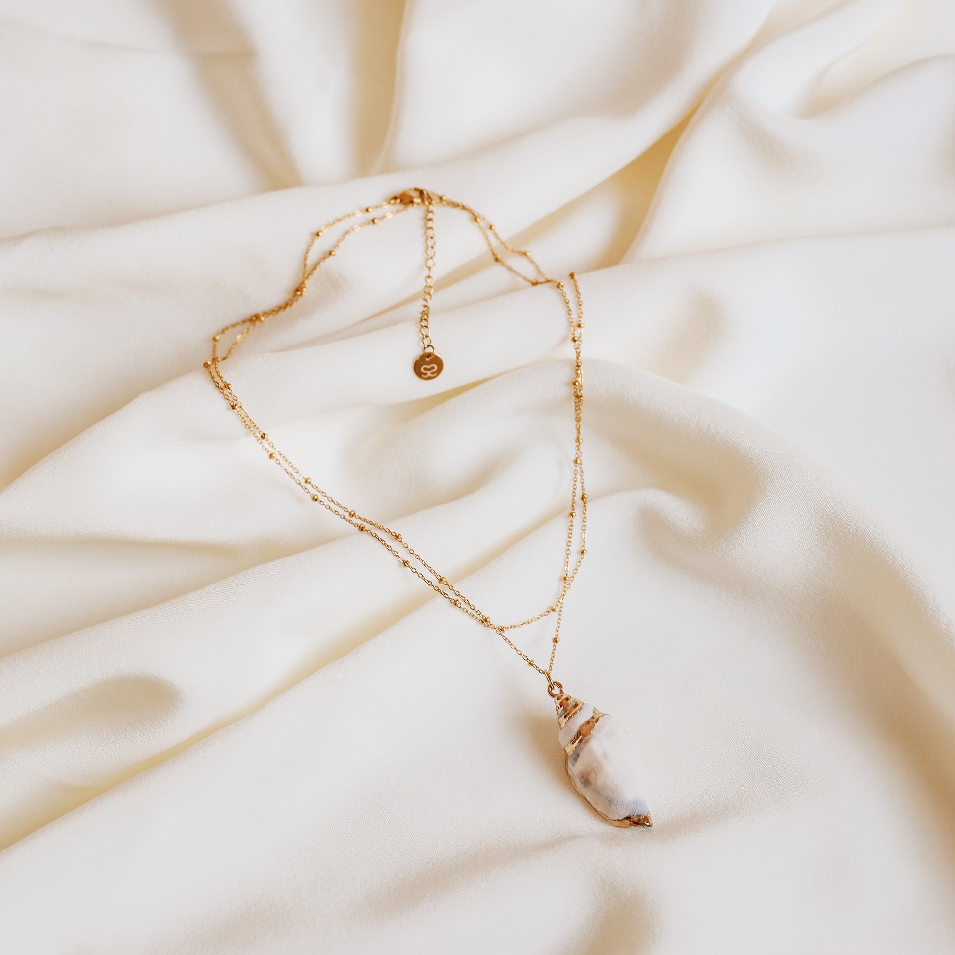 Delicate gold necklace with a real conch shell, perfect for adding ocean-inspired style to any outfit.