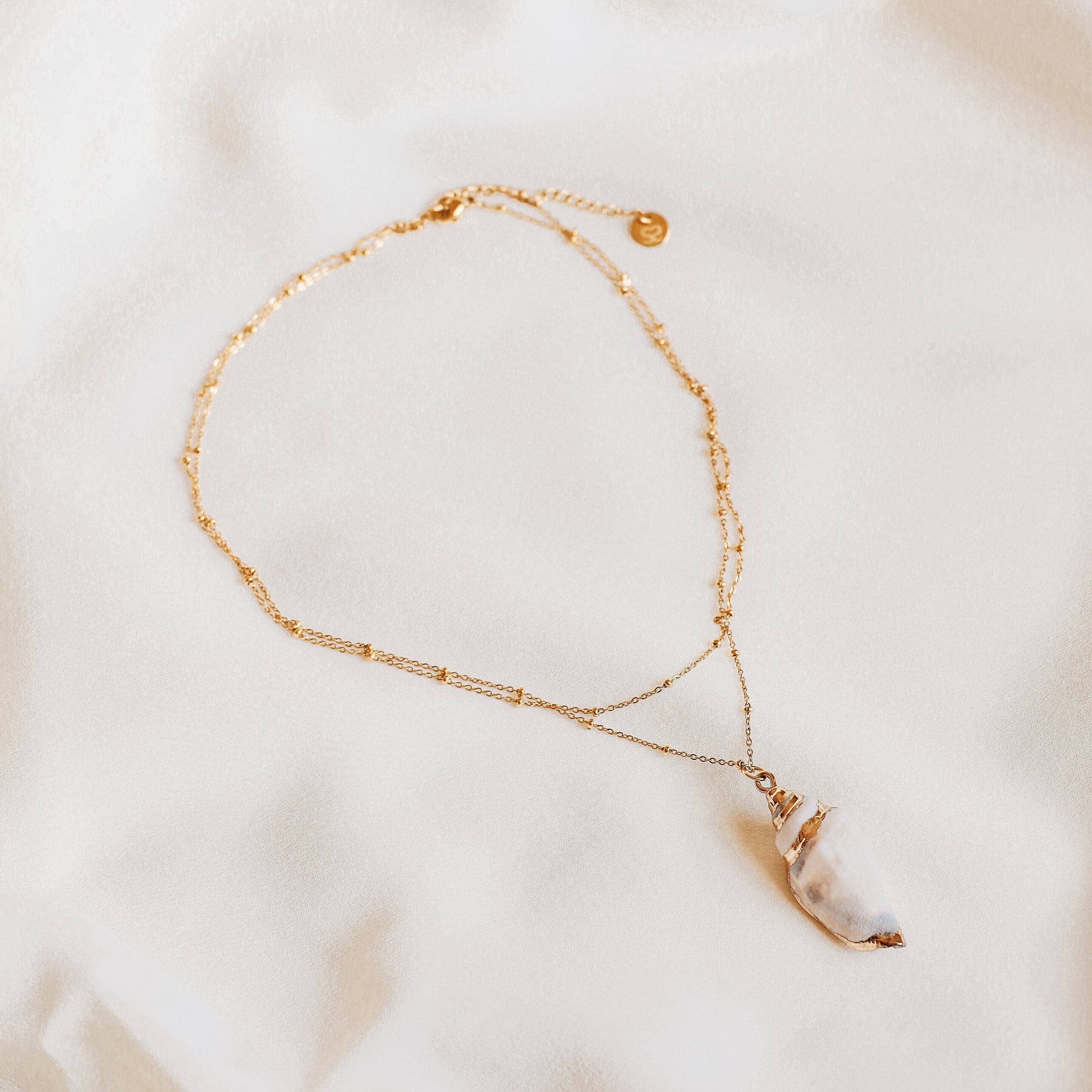 Delicate gold necklace with a real conch shell, perfect for adding ocean-inspired style to any outfit.