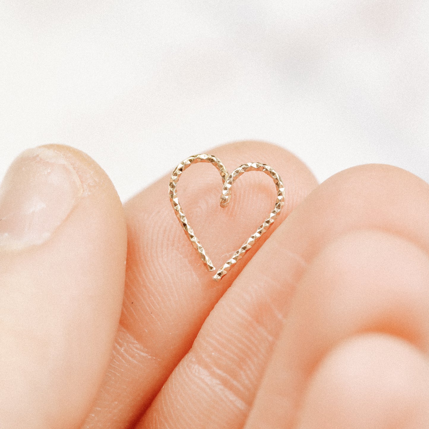 Close-up of an 18k gold plated diamond-cut heart hoop showing the textured finish.